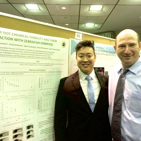REV student Hyo Park in a suit standing in front of his research poster with mentor Prof Zeev Rosenzweig